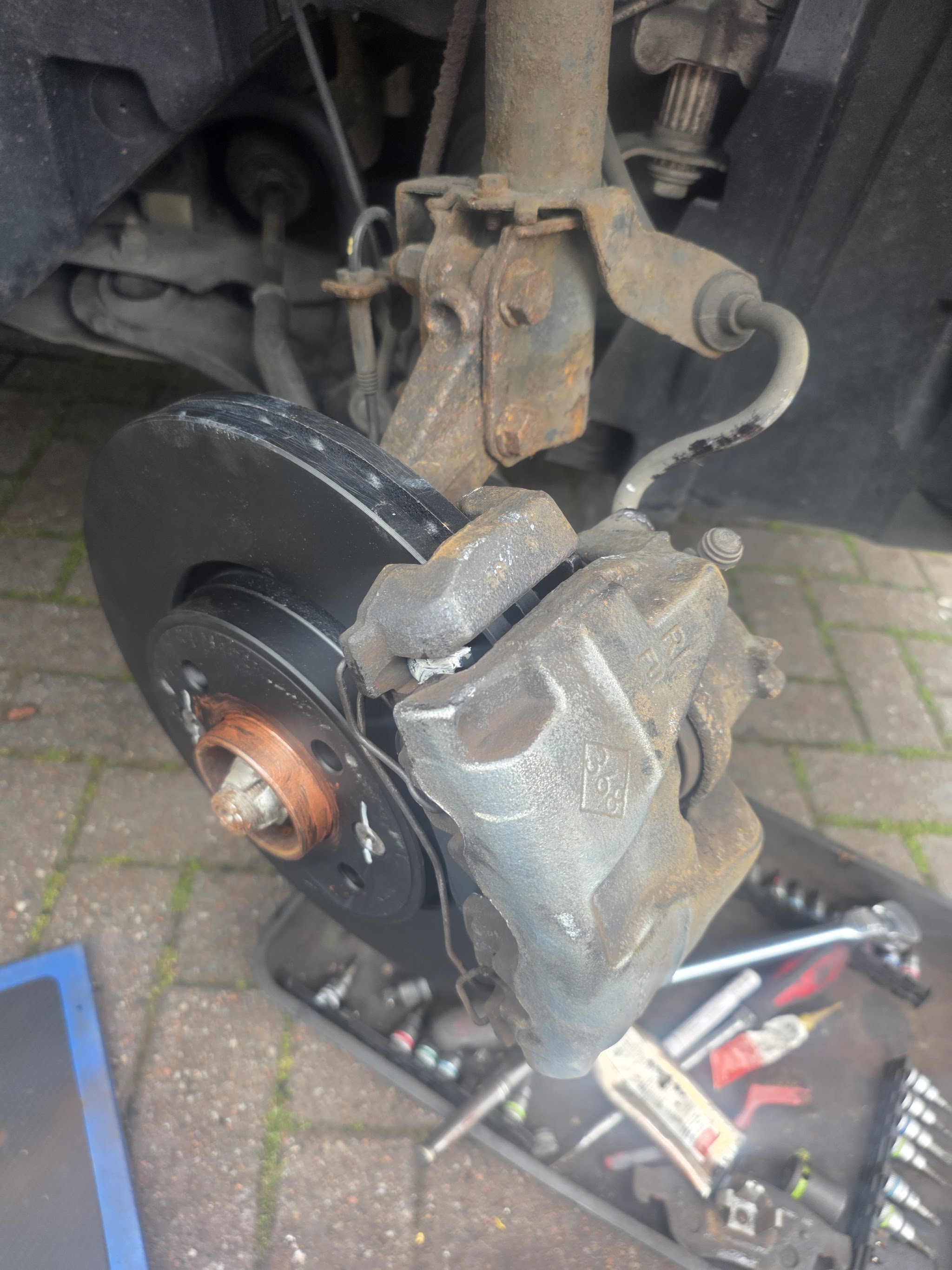 Brake disc and caliper fitted, with tools laid out on a tray